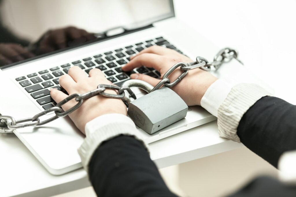 photo of woman locked in chain typing on laptop